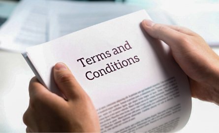 Hands holding paper with terms and conditions written on it. 